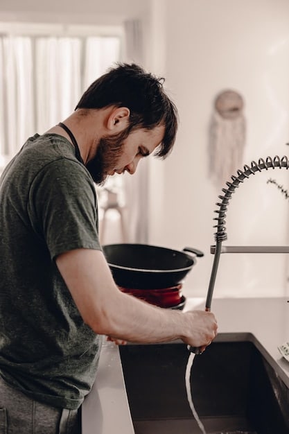A person successfully unclogging a kitchen sink drain with a plunger, with visible debris being dislodged.