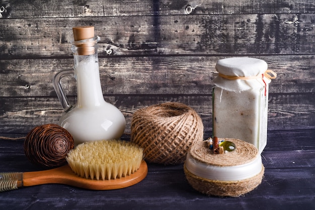 An assortment of beautifully packaged homemade bath products, including bath bombs, bath salts, and sugar scrubs, displayed on a wooden shelf in a well-lit bathroom setting.