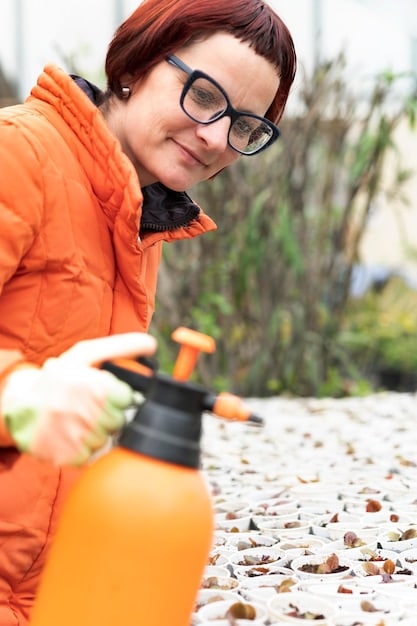 A person spraying a mixture of vinegar and water along a window sill, illustrating the use of natural pest control solutions.