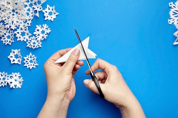 A close-up of hands crafting paper snowflakes, surrounded by colorful construction paper, scissors, and glitter. The warm, inviting light highlights the festive and creative process.