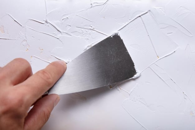 A close-up shot of hands using a spackling knife to smooth joint compound over a small hole in a drywall, showcasing the repair process.