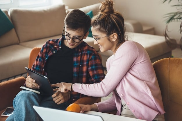 A couple sitting on a couch, looking at a tablet and discussing their finances. They are smiling and engaged in a conversation, showing effective communication and teamwork.