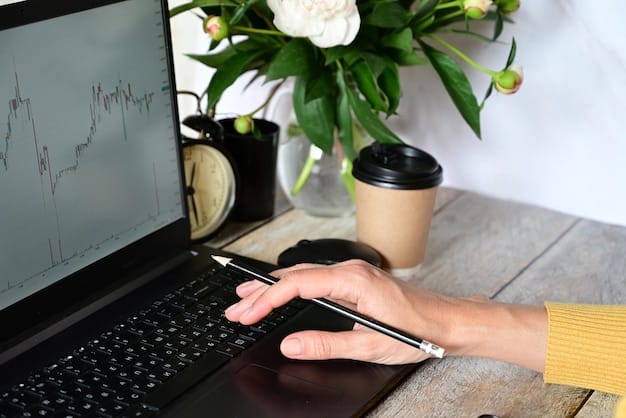 A person's hand holding a pen, pointing at a line item on a budget spreadsheet on a laptop screen, with a cup of coffee and plant nearby, suggesting meticulous financial planning.