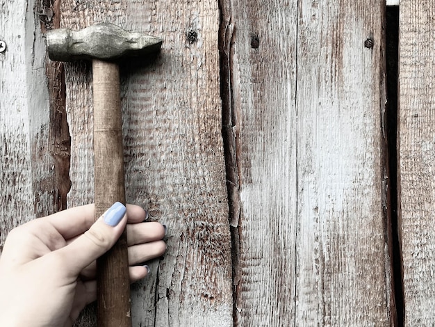 Close-up of hands carefully applying wood filler to a small crack in an old wooden table leg. The wood is light-colored, and the filler is the same shade, blending seamlessly. Tools like a small spatula are visible nearby.