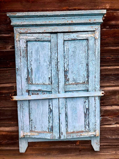 A close-up of a beautifully upcycled vintage wooden cabinet with a distressed teal blue paint finish and new gold geometric hardware. One of the cabinet doors is slightly ajar, revealing organized storage inside. The overall look is chic and modern with a bohemian touch.