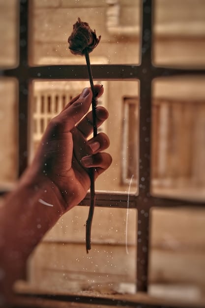 A close-up of a hand using an incense stick to detect a draft around a window frame, emphasizing the subtle nature of air leaks.