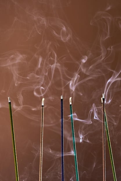 A close-up of an incense stick held near a closed window frame, with smoke visibly bending inwards, illustrating a draft detection technique.